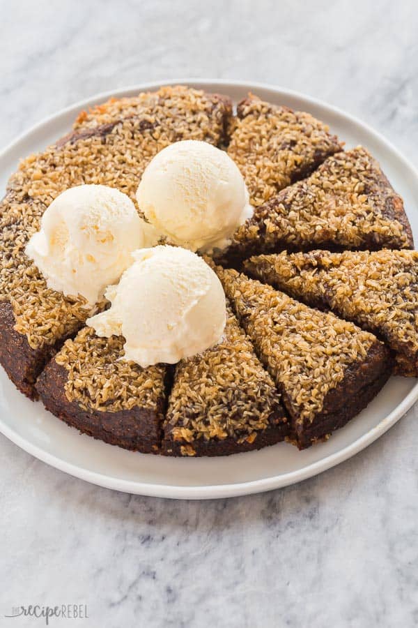 coconut date cake with 3 scoops of vanilla ice cream on white plate