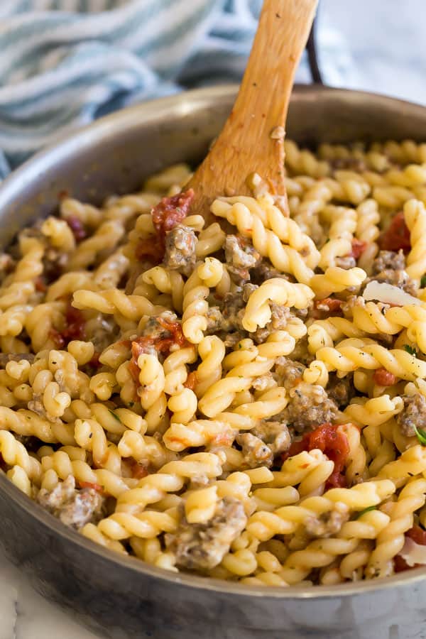 close up image of pasta in pan with wooden spoon