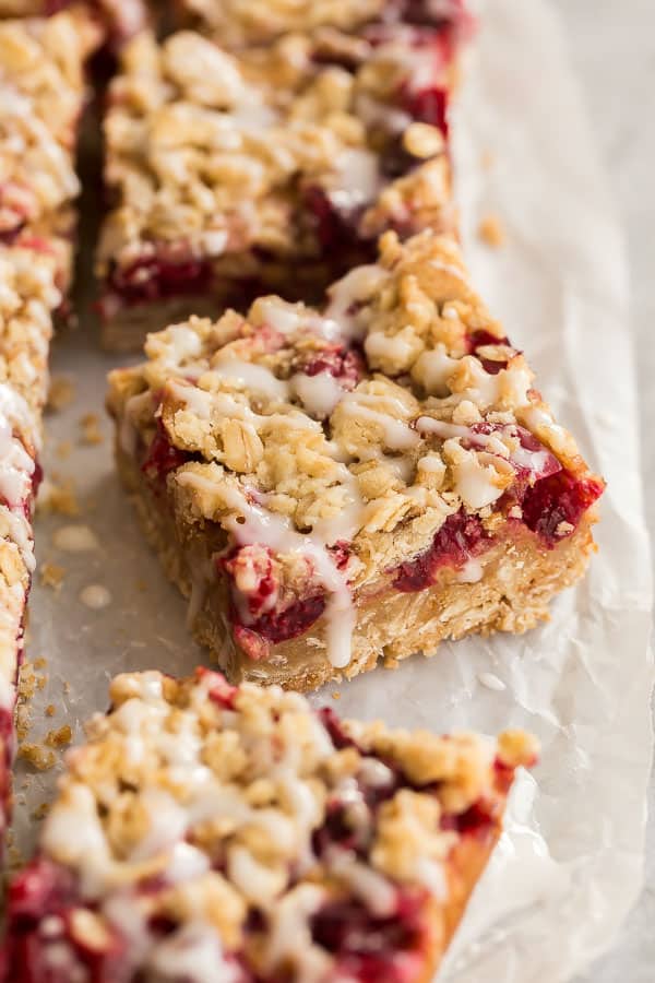 These Cranberry Caramel Bars have a crumbly oat crust, filled with tart cranberries and sweet caramel -- a match made in heaven! #dessert #cranberry #christmas #recipes close up image of one cranberry bar with drizzle of glaze