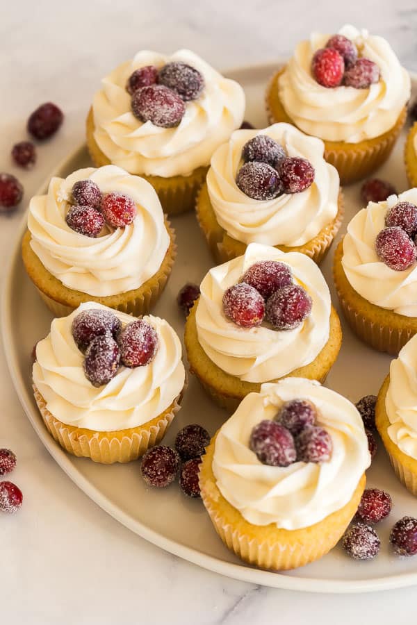 Vanilla cupcakes, filled with homemade cranberry filling and topped with a swirl of white chocolate frosting -- the perfect festive holiday treat! #cranberry #thanksgiving #christmas #cupcakes #dessert white chocolate cranberry cupcakes with sugared cranberries