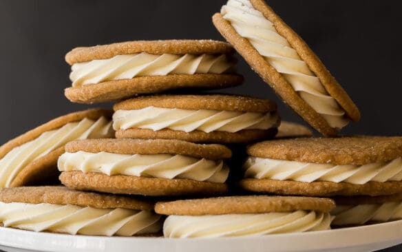 white chocolate gingersnap oreos piled on a white cake plate