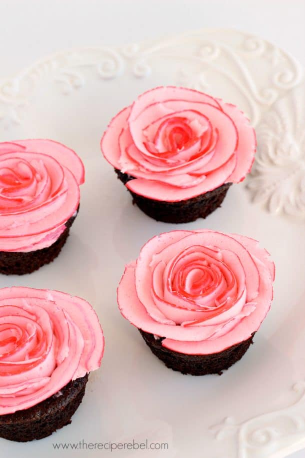 white platter with four chocolate cupcakes and pink frosting roses