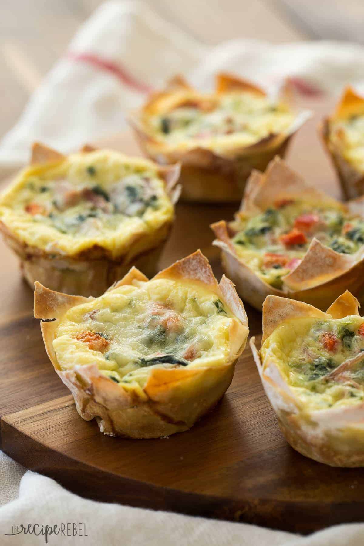 mini wonton quiche with spinach and peppers on a wooden board