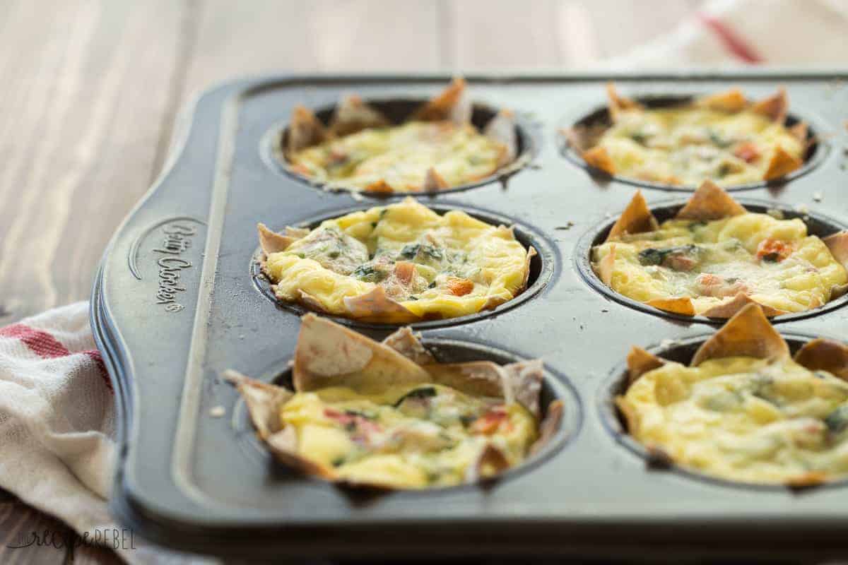 muffin pan with six mini wonton quiche in the cups on a wooden board
