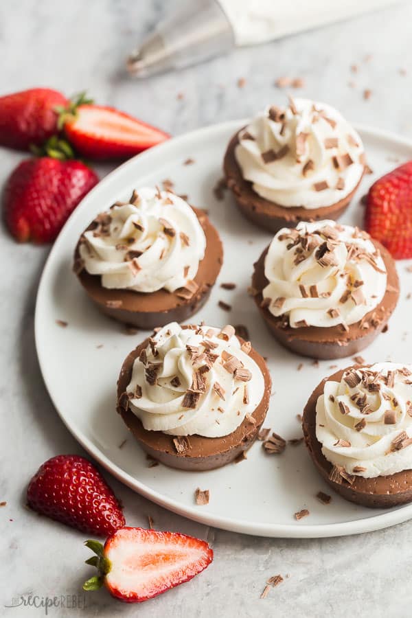 mini cheesecakes on white plate with fresh strawberries all around