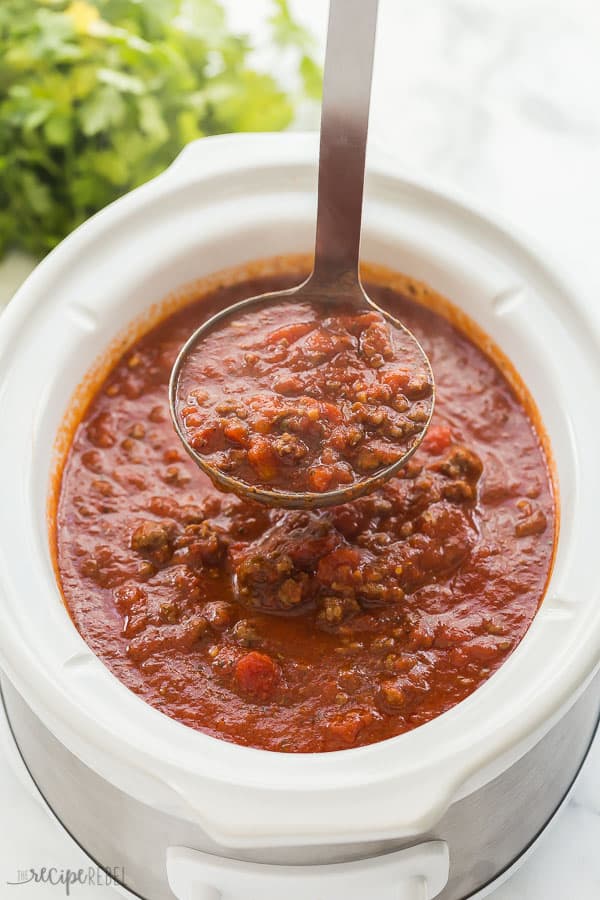 slow cooker spaghetti sauce in white crockpot with metal scoop scooping sauce