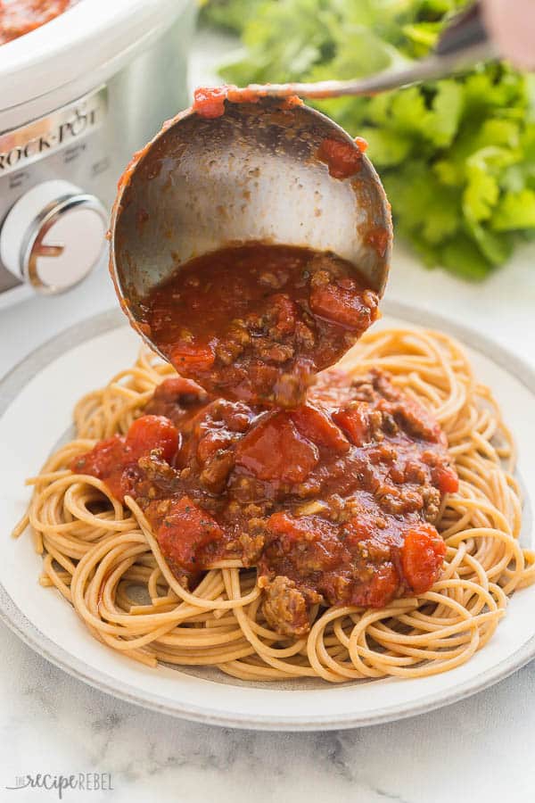 crockpot spaghetti sauce being spooned over pasta on grey plate