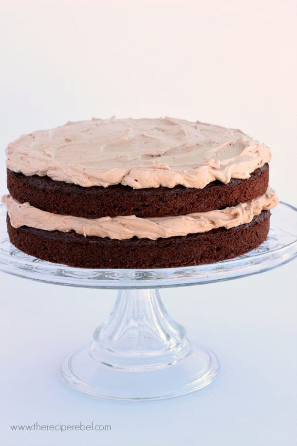 two layer mexican chocolate cake with milk chocolate frosting on clear glass cake plate