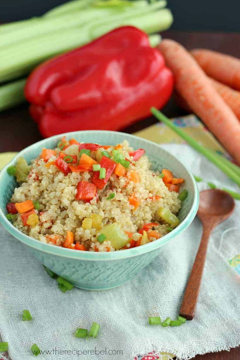 light blue bowl filled with quinoa pilaf topped with peppers and green onions
