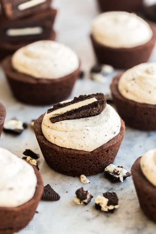 frosted oreo cookie cups on marble with piece of oreo cookie on top