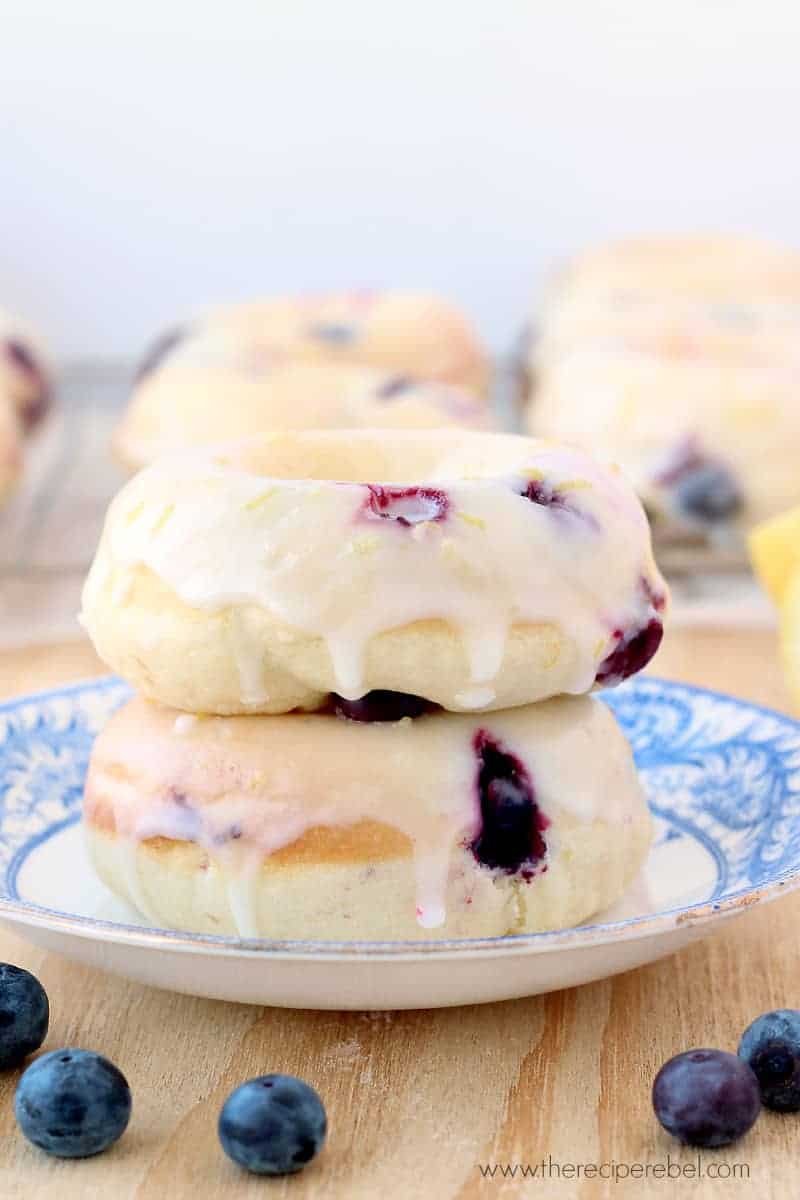 two lemon blueberry baked donuts stacked on a white and blue plate