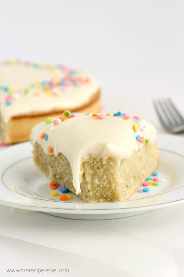 slice of coconut cake on white plate with a bite taken off the end