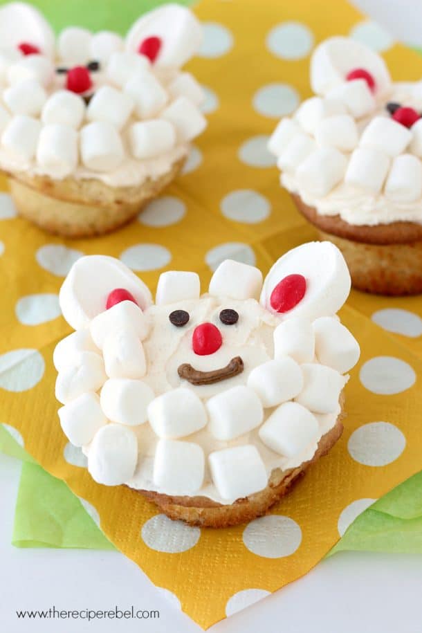 cupcakes decorated with white frosting mini marshmallows and jelly beans to look like a lamb