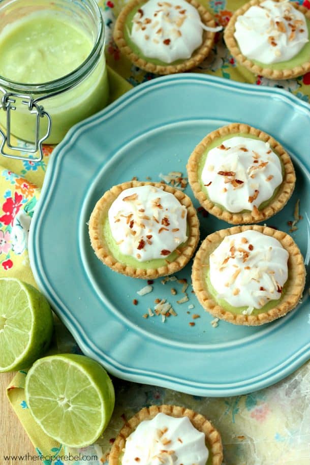 overhead image of blue plate with three coconut lime tarts and lime halves on the side