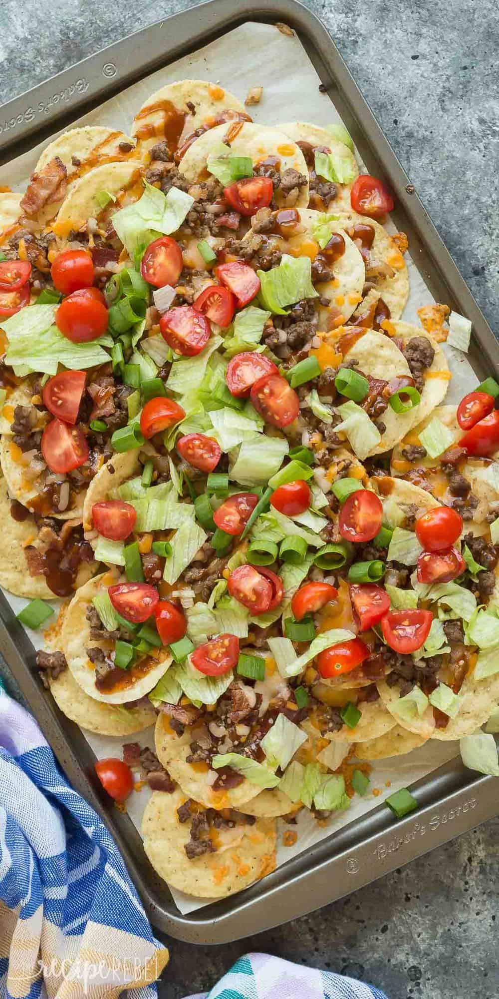 BBQ Bacon Cheeseburger Nachos are the best BBQ nachos you've ever had! Barbecue sauce, ground beef, bacon, cheddar cheese, green onions and all the burger toppings you want. Perfect for movie night or game day! Includes step by step RECIPE VIDEO. #nachos #appetizer #groundbeef #beef #recipe #recipes