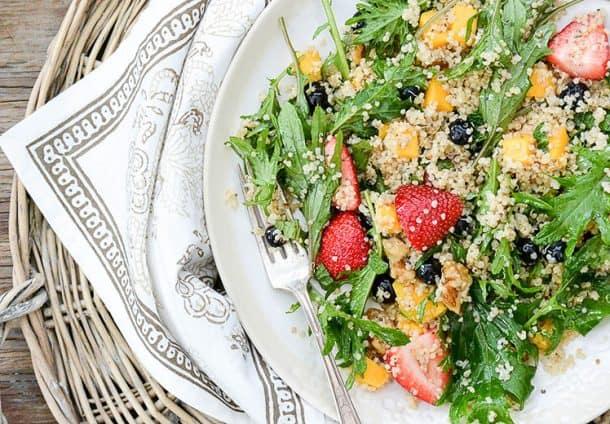 berry arugula salad with quinoa on a white plate