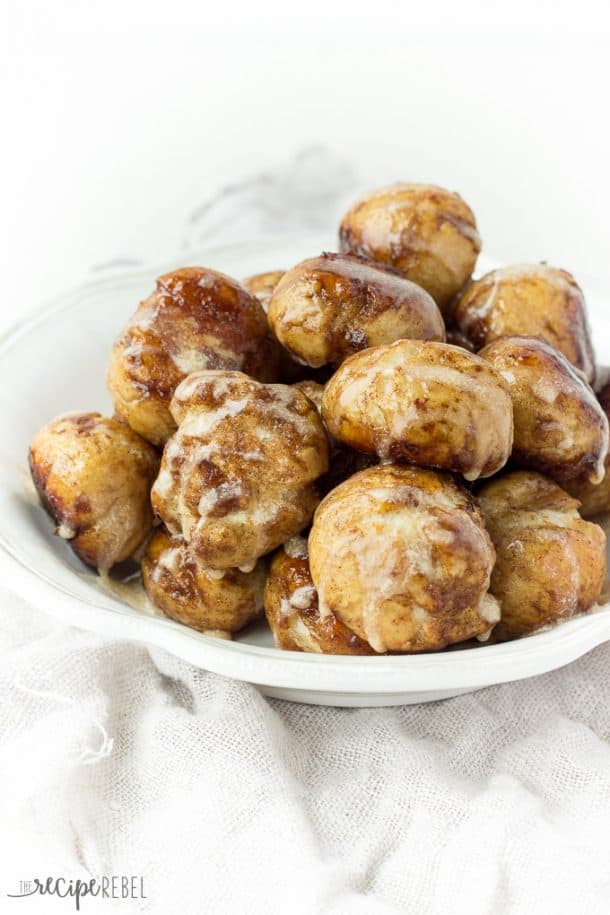 soft pretzel bites on a white plate coated in cinnamon sugar and drizzled with glaze