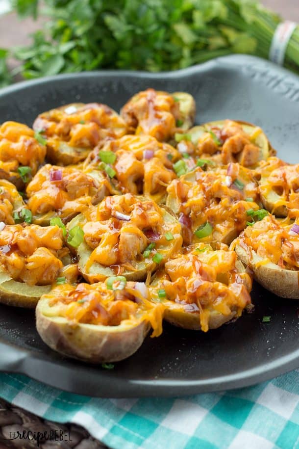 Grilled BBQ Chicken Potato Skins: BBQ chicken, pineapple, red onion, barbecue sauce and cheese, all loaded up in a tender potato shell, and grilled on the barbecue! The perfect summer appetizer or picnic lunch. www.thereciperebel.com bbq chicken potato skins on grill pan with melted cheese and green onions