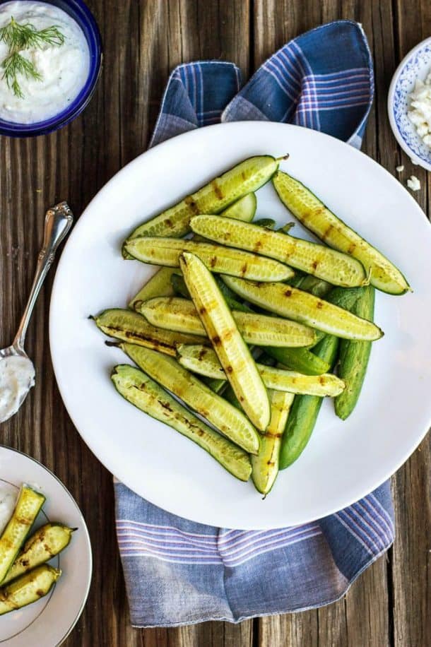 grilled mini cucumbers on white plate on top of blue towel