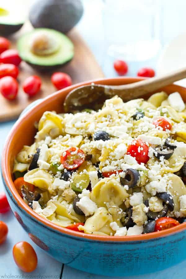 tortellini pasta salad in blue bowl with wooden spoon