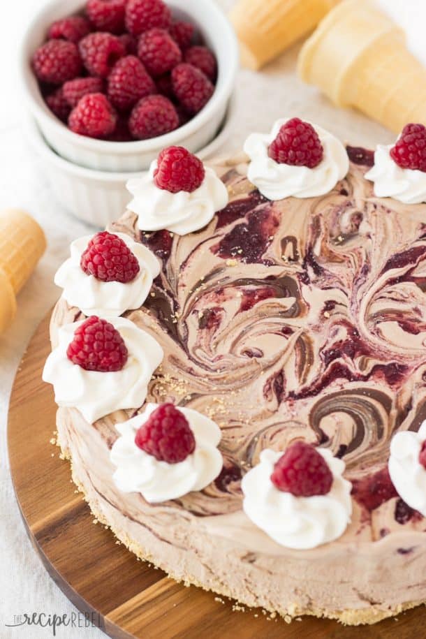 whole nutella raspberry ice cream cake on wooden cutting board with fresh raspberries