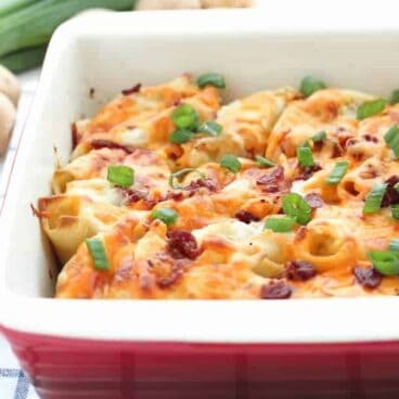 Perogy Stuffed Shells: garlic herb mashed potatoes and cheddar cheese stuffed inside a large pasta shell, and topped with creamy Béchamel sauce, more cheddar cheese and bacon before baking. An indulgent, make-ahead side dish that’s perfect for leftover mashed potatoes! www.thereciperebel.com