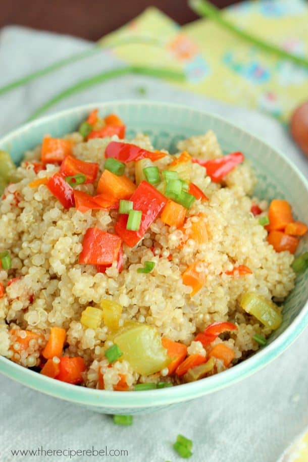 quinoa pilaf in blue bowl with peppers and green onions on top