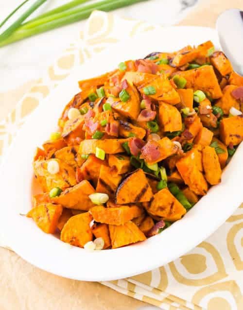 grilled sweet potato salad in white bowl with bacon and green onions