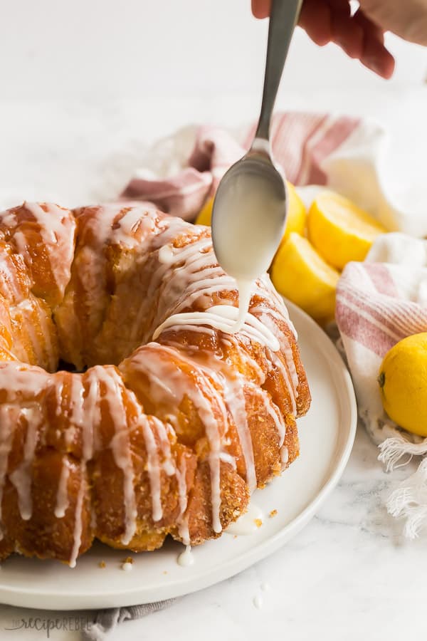 This Glazed Lemon Monkey Bread is made with homemade bun dough rolled in lemon sugar, baked, and covered in a thick lemon glaze. The perfect make ahead breakfast, brunch or dessert! #lemon #bread #breakfast #baking lemon monkey bread drizzled with glaze