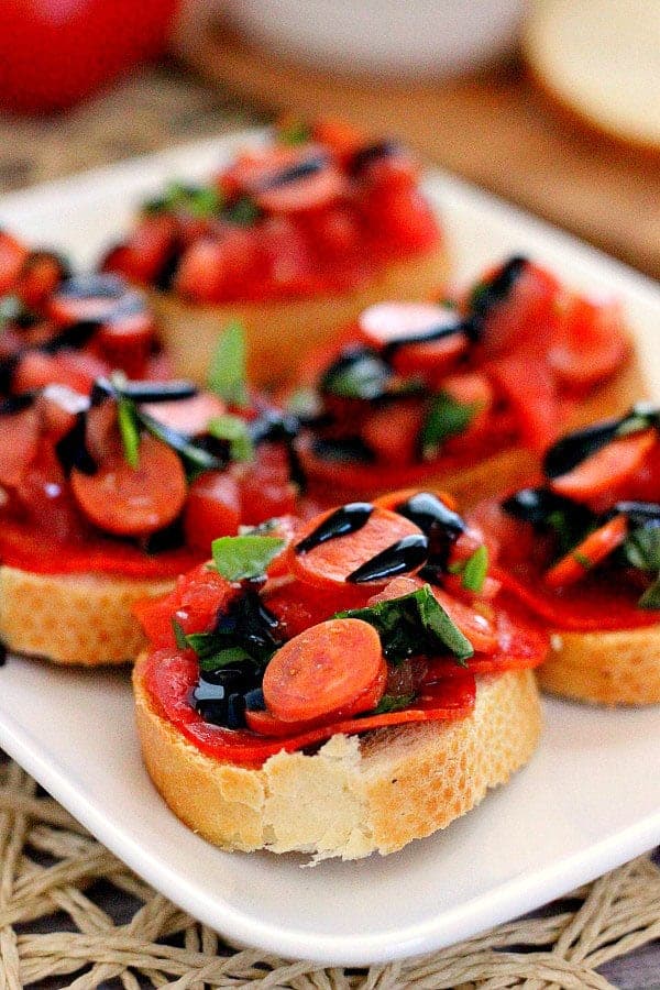 pepperoni bruschetta on white plate with balsamic drizzle