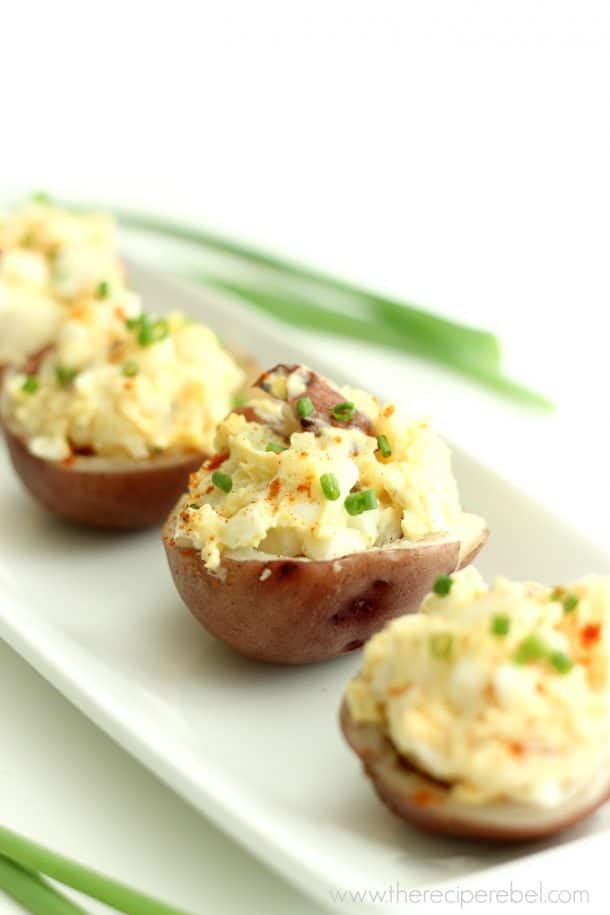 potato salad bites lined up on white plate topped with green onions