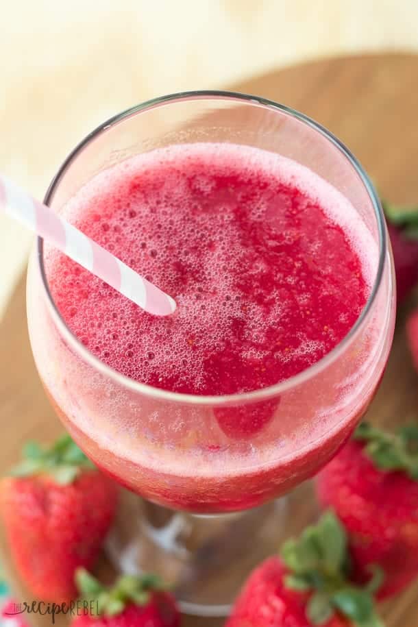Easy 2-Ingredient Skinny Slush: The easiest way to make a skinny, slushy summer drink! Plus TEN other flavor combinations. Mix and match to make any flavor combo you want – you’ll never run out of options this summer! www.thereciperebel.com up close image of skinny pink slush in glass with pink paper straw