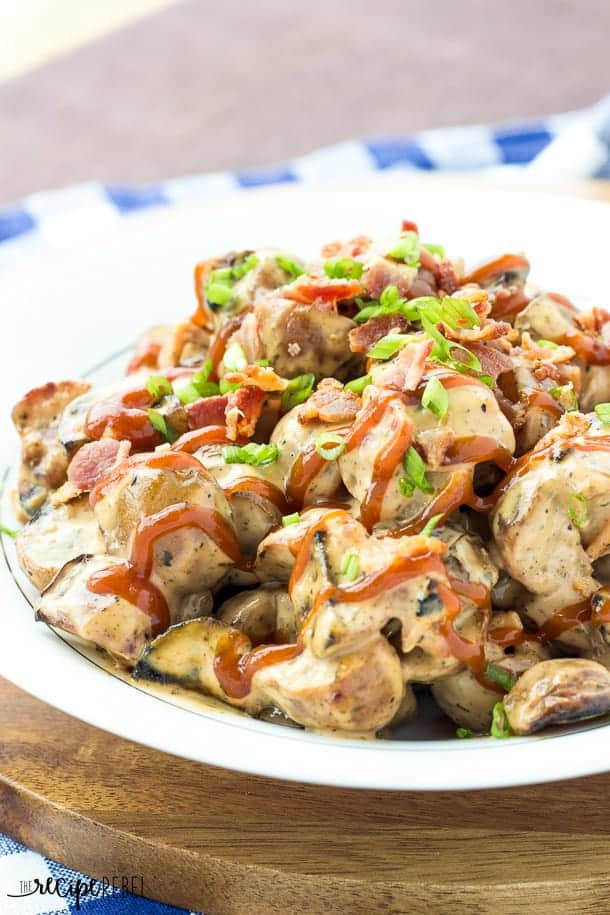 close up image of bbq bacon potato salad with barbecue sauce drizzle green onions and bacon