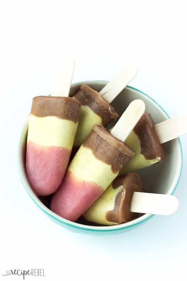 blue bowl filled with banana split pudding pops on wooden popsicle sticks