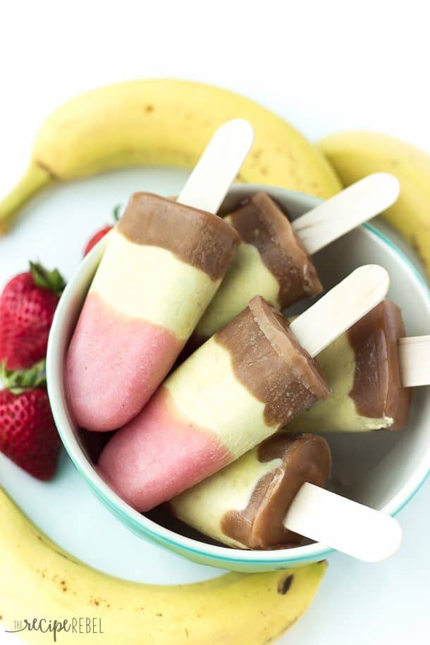 banana split pudding pops in a bowl with fresh strawberries and bananas on the side
