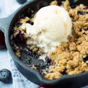 Berry Cherry Crisp: Fresh cherries and blueberries topped with an oatmeal cookie crumble and baked until golden and crunchy! The perfect summer dessert for all of that beautiful fruit! Perfect for topping with ice cream. www.thereciperebel.com