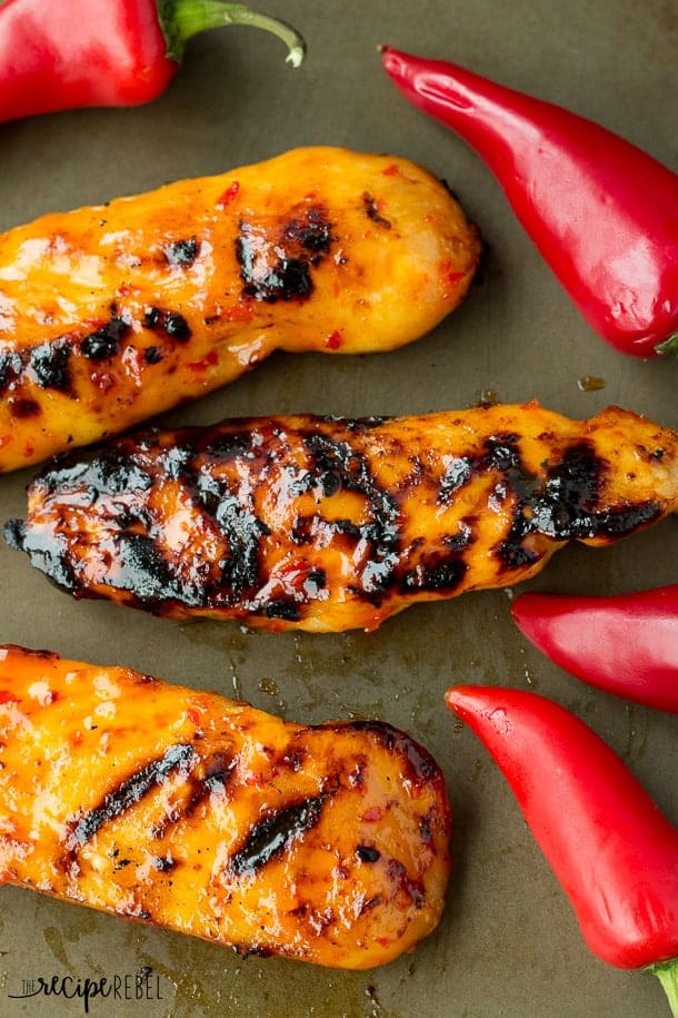 overhead image of grilled chicken pieces with red chilis all around