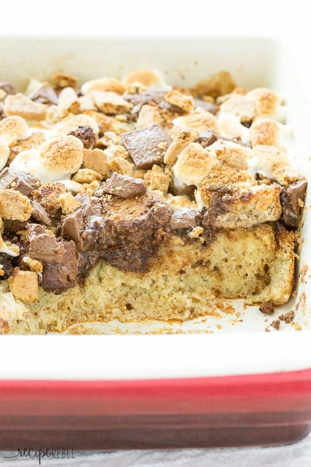 pan of smores french toast casserole with scoop missing with melted chocolate and toasted marshmallows on top