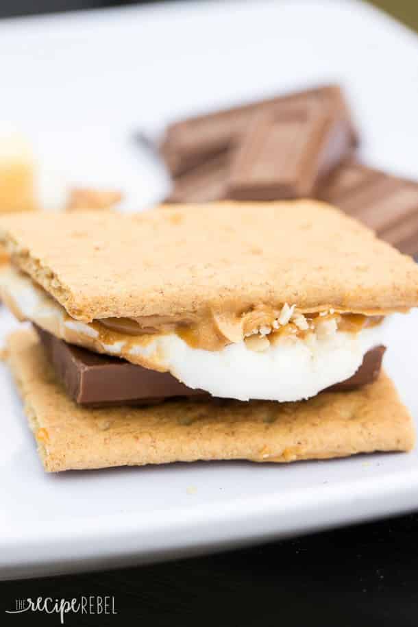 caramel peanut butter smore on white plate with chocolate bars behind