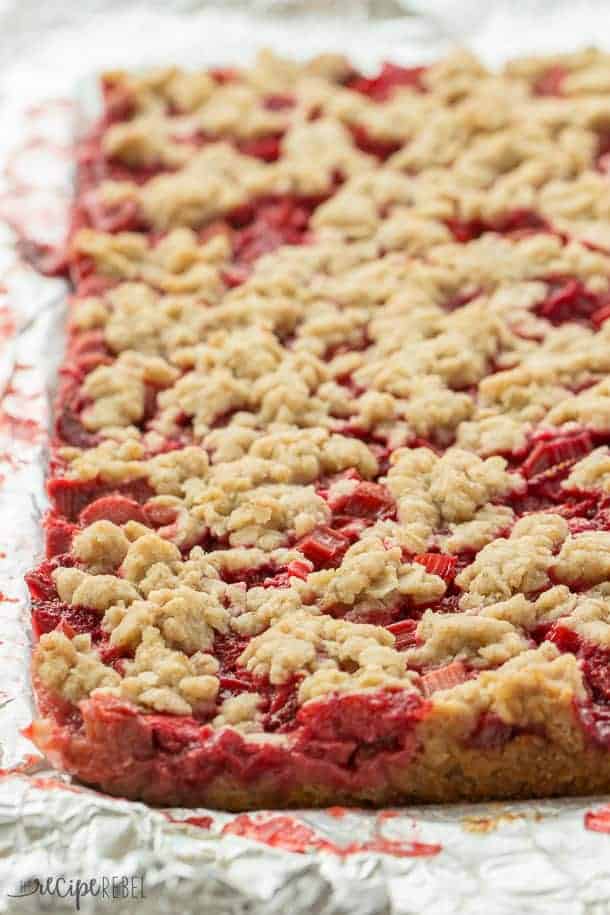 Strawberry Rhubarb Crisp Bars: Oatmeal cookie base topped with sweet and tangy strawberries and rhubarb topped with more oatmeal cookie topping -- your favorite summer dessert is now a portable treat or back to school snack! www.thereciperebel.com strawberry rhubarb crisp bars whole uncut