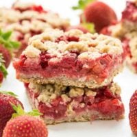 Strawberry Rhubarb Crisp Bars: Oatmeal cookie base topped with sweet and tangy strawberries and rhubarb topped with more oatmeal cookie topping -- your favorite summer dessert is now a portable treat or back to school snack! www.thereciperebel.com