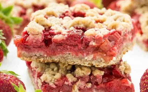 Strawberry Rhubarb Crisp Bars: Oatmeal cookie base topped with sweet and tangy strawberries and rhubarb topped with more oatmeal cookie topping -- your favorite summer dessert is now a portable treat or back to school snack! www.thereciperebel.com