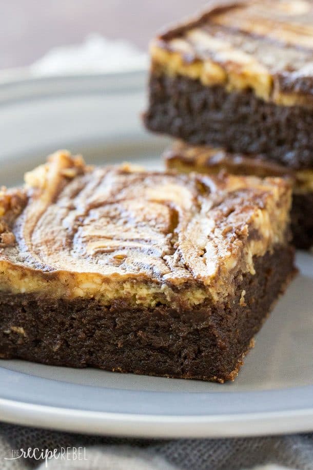 Flourless Pumpkin Cheesecake Brownies: Fudgy flourless brownies topped with pumpkin cheesecake -- a naturally gluten free treat that's perfect for Thanksgiving or the holidays! www.thereciperebel.com close up image of brownie with pumpkin cream cheese layer swirled on top