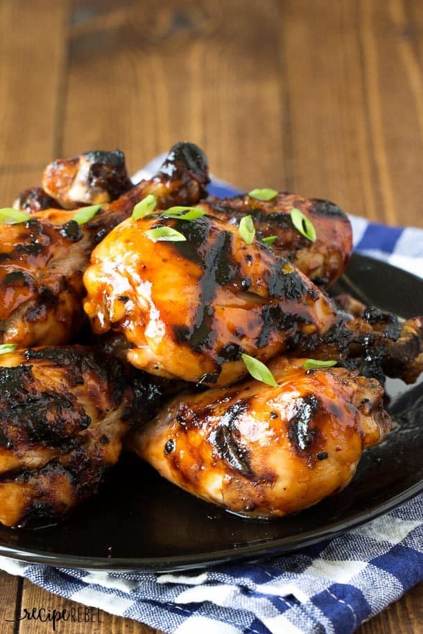 maple glazed grilled chicken drumsticks on black plate with green onions