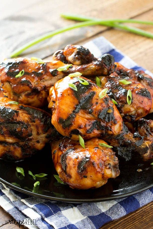chicken drumsticks with grill marks and sticky glaze on black plate over blue checked napkin
