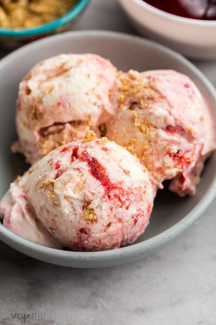 three scoops of cherry cheesecake ice cream in a grey bowl