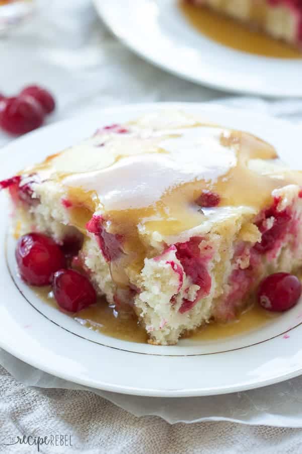 up close image of a piece of cranberry cake on white plate with caramel sauce poured over