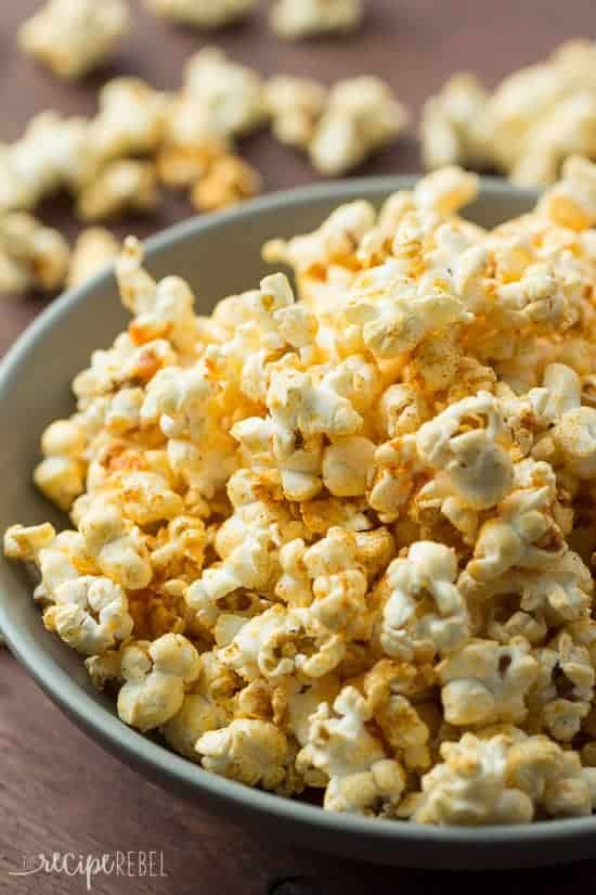 close up image of nacho popcorn in grey bowl with popcorn scattered in the background