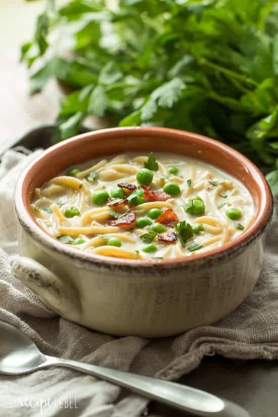 bowl of turkey tetrazzini soup with peas and bacon on top and parsley bunch in the background