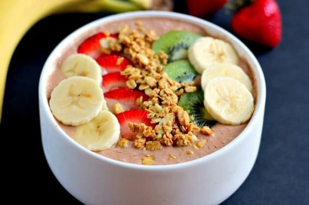 chocolate peanut butter smoothie bowl topped with banana strawberry kiwi and granola
